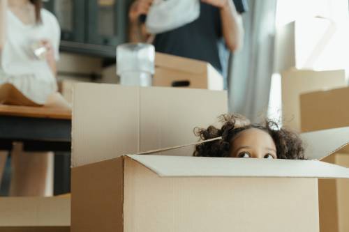 Little girl hiding in a moving box