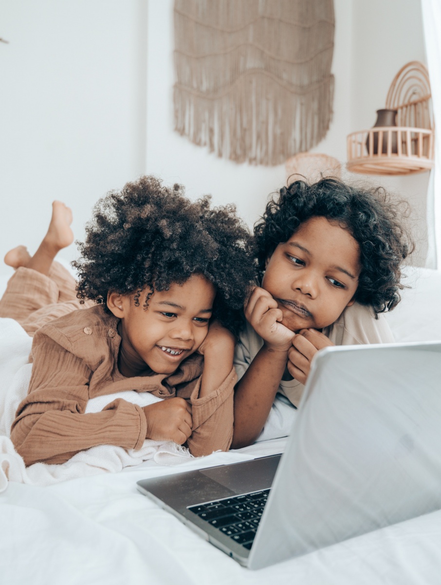 Two kids looking at a laptop smiling.